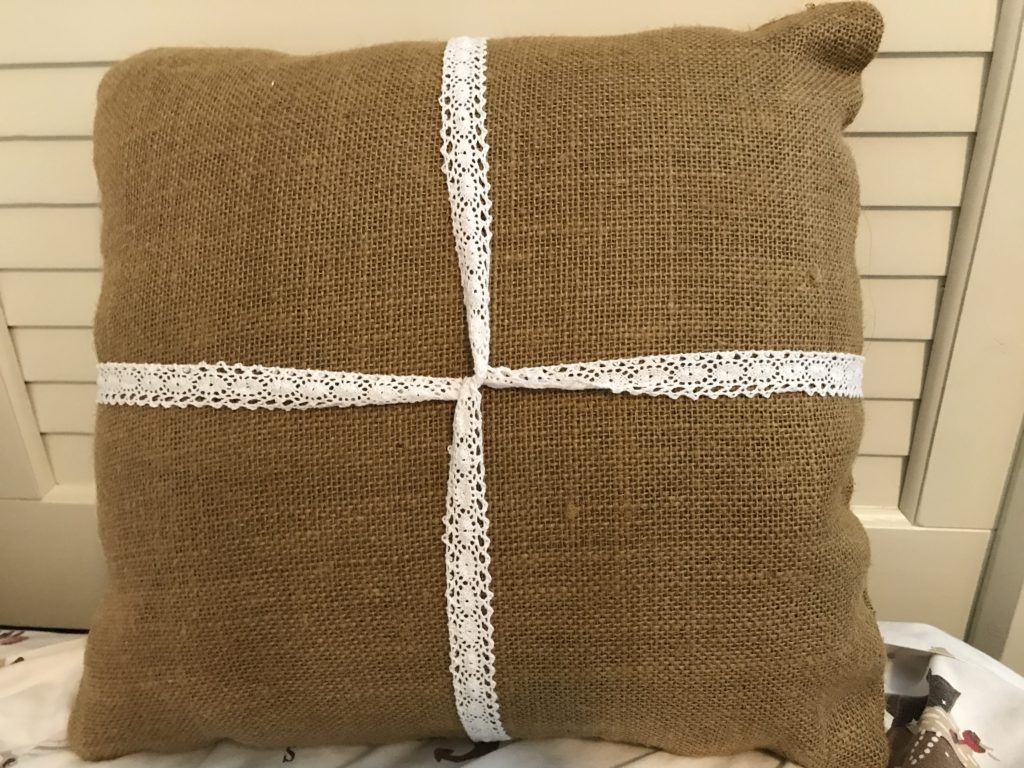 Burlap pillow with white lace ribbon. Step 1 of upgrading front porch pillow into a burlap front porch rocking chair Christmas pillow.